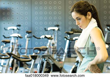 Woman standing in front of exercise bikes, hands on hips View Large Photo Image Stock Photo - Woman standing in front of exercise bikes, hands on hips. Fotosearch