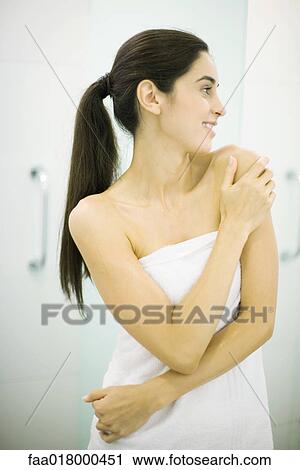 Woman standing wrapped in towel, hand on shoulder, looking away View Large Photo Image Stock Image - Woman standing wrapped in towel, hand on shoulder, looking away. Fotosearch
