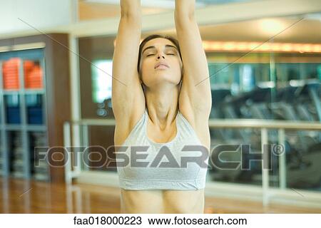 Stock Image - Woman stretching arms over head, eyes closed. Fotosearch