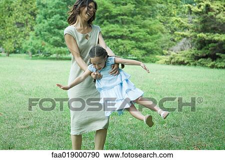 Woman swinging little girl around on grass View Large Photo Image Stock Image - Woman swinging little girl around on grass. Fotosearch