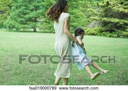 Woman swinging little girl around on grass View Large Photo Image Stock Photo - Woman swinging little girl around on grass. Fotosearch