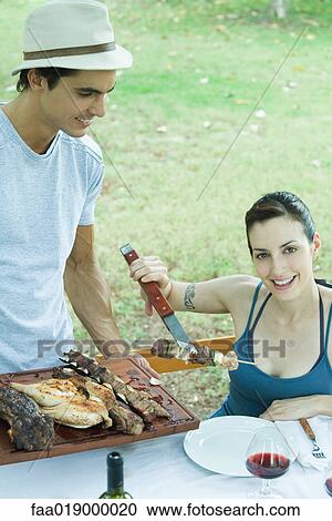 Woman taking kebab from tray of grilled meats, smiling at camera View Large Photo Image Stock Image - Woman taking kebab from tray of grilled meats, smiling at camera. Fotosearch