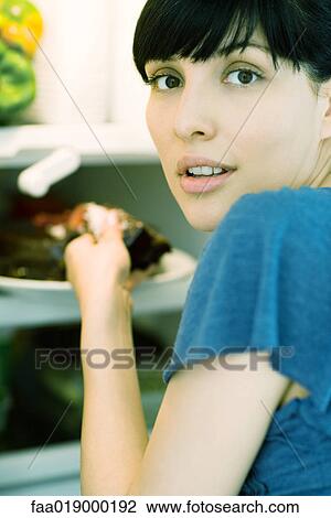 Woman taking piece of cake from refrigerator, looking over shoulder at camera View Large Photo Image Stock Image - Woman taking piece of cake from refrigerator, looking over shoulder at camera. Fotosearch