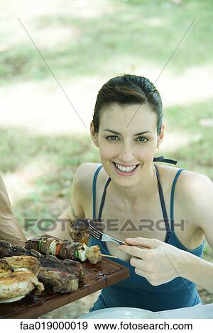 Woman taking piece of grilled meat from tray, smiling at camera View Large Photo Image Stock Photo - Woman taking piece of grilled meat from tray, smiling at camera. Fotosearch