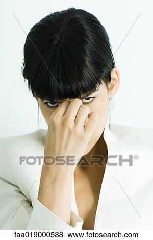 Woman touching bridge of nose, glaring at camera, portrait View Large Photo Image Stock Photo - Woman touching bridge of nose, glaring at camera, portrait. Fotosearch