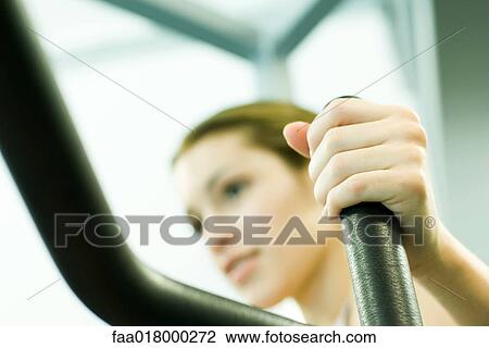 Stock Image - Woman using weight machine. Fotosearch