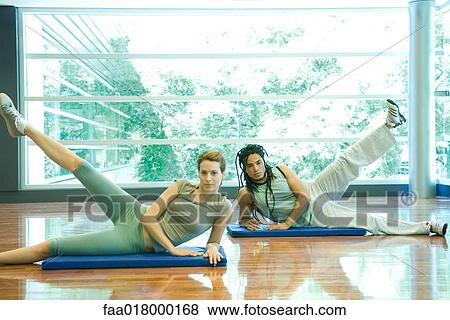 Stock Photo - Young adults doing leg lifts in exercise class. Fotosearch