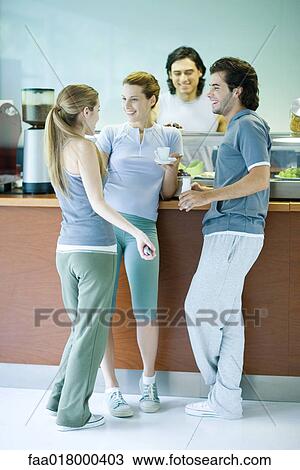 Young adults dressed in exercise clothes, standing by snack bar, chatting View Large Photo Image Stock Image - Young adults dressed in exercise clothes, standing by snack bar, chatting. Fotosearch