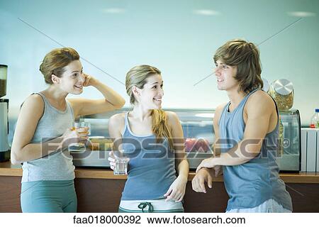 Young adults wearing exercise clothes, standing in cafeteria, having healthy snack and chatting View Large Photo Image Stock Image - Young adults wearing exercise clothes, standing in cafeteria, having healthy snack and chatting. Fotosearch
