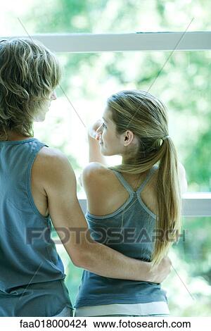 Picture - Young couple in exercise clothing standing by window. Fotosearch