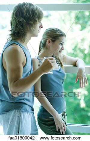 Stock Image - Young couple in exercise clothing standing by window. Fotosearch