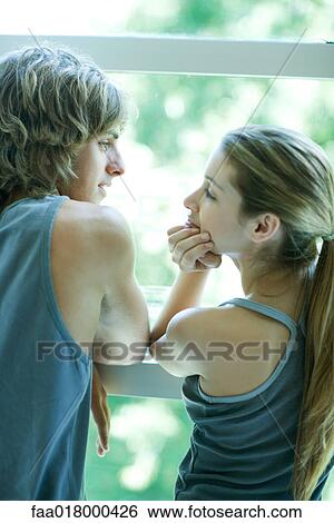 Young couple in exercise clothing standing by window, looking at each other View Large Photo Image Stock Photograph - Young couple in exercise clothing standing by window, looking at each other. Fotosearch