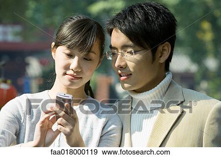 Stock Photo - Young couple looking at cell phone. Fotosearch