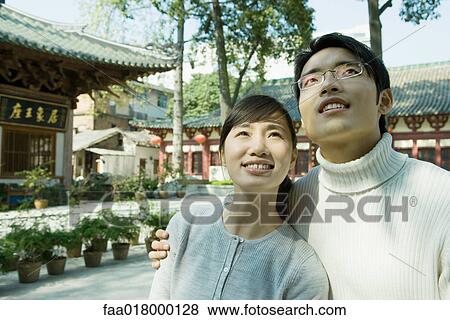 Stock Photo - Young couple, looking up, portrait. Fotosearch