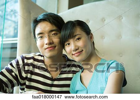 Stock Photo - Young couple sitting in booth, smiling at camera. Fotosearch