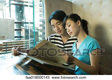 Young couple sitting in restaurant, holding menu View Large Photo Image Stock Image - Young couple sitting in restaurant, holding menu. Fotosearch