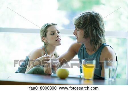 Young couple wearing exercise clothes, sitting side by side, having healthy snack and looking at magazine View Large Photo Image Stock Image - Young couple wearing exercise clothes, sitting side by side, having healthy snack and looking at magazine. Fotosearch