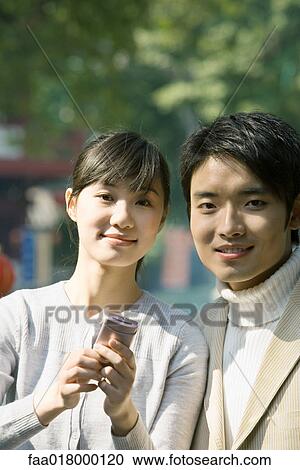 Young couple with cell phone, smiling at camera, portrait View Large Photo Image Stock Image - Young couple with cell phone, smiling at camera, portrait. Fotosearch