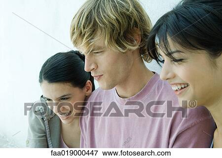 Young friends looking out of frame, side view View Large Photo Image Stock Photo - Young friends looking out of frame, side view. Fotosearch