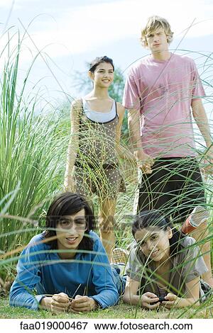Stock Photo - Young friends lying and walking in grass. Fotosearch