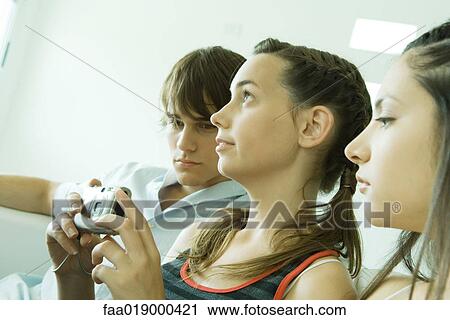Stock Image - Young friends, one holding digital camera. Fotosearch