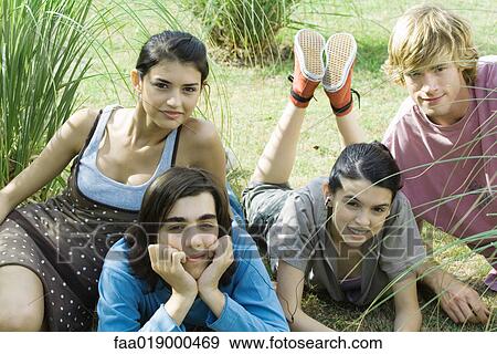 Stock Photo - Young friends reclining on grass, smiling at camera. Fotosearch