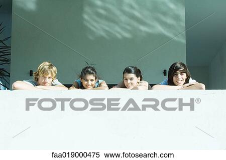 Young friends resting heads on arms, smiling at camera View Large Photo Image Stock Photography - Young friends resting heads on arms, smiling at camera. Fotosearch
