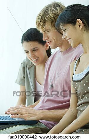 Young friends using laptop together View Large Photo Image Stock Image - Young friends using laptop together. Fotosearch