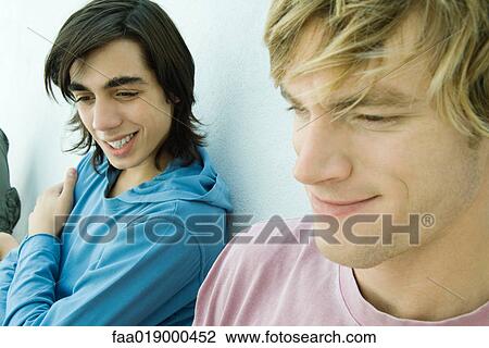 Stock Image - Young man and teen boy smiling, close-up. Fotosearch