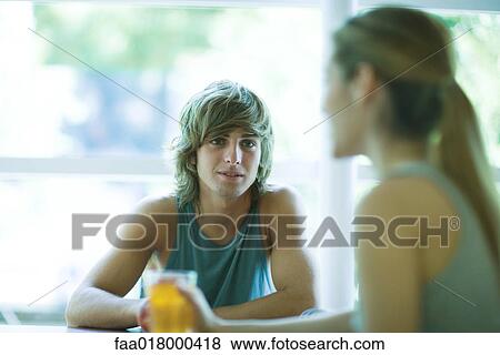 Young man and woman in exercise clothes, sitting having drinks, chatting, focus on man View Large Photo Image Stock Photo - Young man and woman in exercise clothes, sitting having drinks, chatting, focus on man. Fotosearch