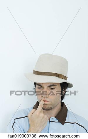 Young man biting finger, looking down View Large Photo Image Stock Photograph - Young man biting finger, looking down. Fotosearch