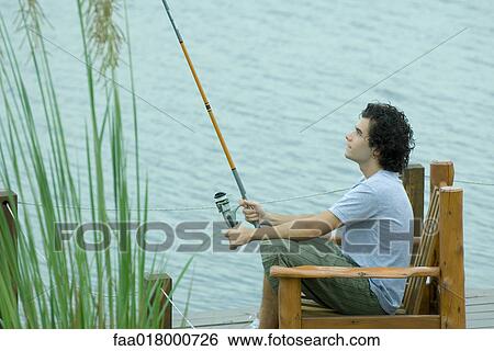 Stock Photograph - Young man fishing on dock. Fotosearch