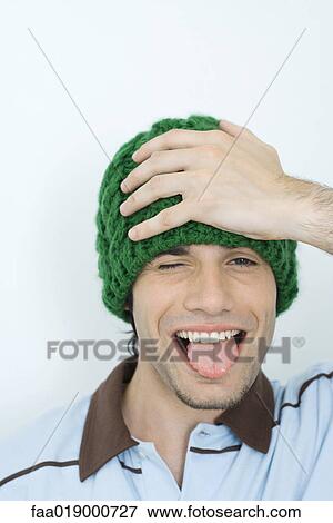 Young man holding head and sticking out tongue, portrait View Large Photo Image Stock Photo - Young man holding head and sticking out tongue, portrait. Fotosearch