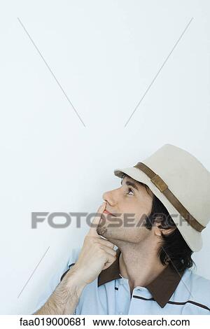 Young man wearing hat, finger over lips, looking up View Large Photo Image Stock Image - Young man wearing hat, finger over lips, looking up. Fotosearch