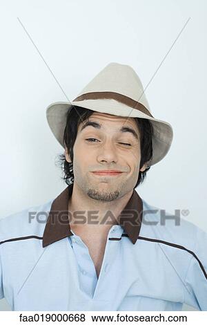Young man wearing hat, winking at camera, portrait View Large Photo Image Stock Photo - Young man wearing hat, winking at camera, portrait. Fotosearch