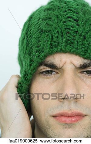 Young man wearing knit hat, furrowing brow, portrait, close-up View Large Photo Image Stock Photography - Young man wearing knit hat, furrowing brow, portrait, close-up. Fotosearch