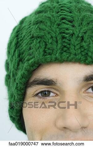 Stock Photo - Young man wearing knit hat, portrait, close-up, partial view of face. Fotosearch