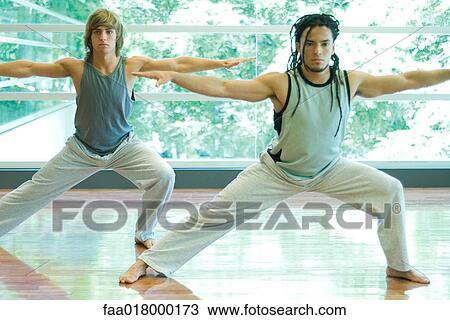 Stock Image - Young men doing side lunge in exercise class. Fotosearch