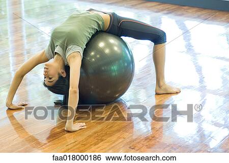 Stock Photograph - Young woman doing backbend on fitness ball. Fotosearch