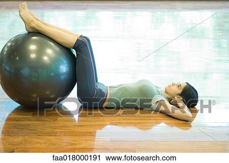 Young woman doing sit-ups with legs resting on fitness ball View Large Photo Image Stock Image - Young woman doing sit-ups with legs resting on fitness ball. Fotosearch