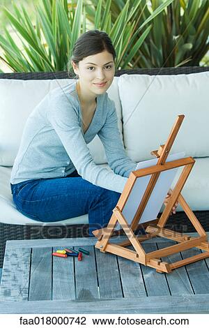 Stock Image - Young woman drawing with easel. Fotosearch