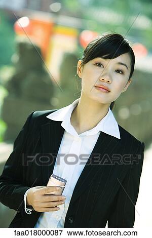 Stock Photo - Young woman holding cell phone, portrait. Fotosearch