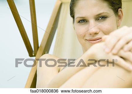 Stock Photograph - Young woman lounging in beach chair, smiling at camera. Fotosearch