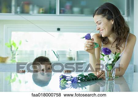 Stock Photo - Young woman making fresh flower arrangement, smiling at boy. Fotosearch