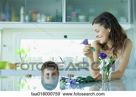 Stock Photo - Young woman making fresh flower arrangement, smiling at boy. Fotosearch