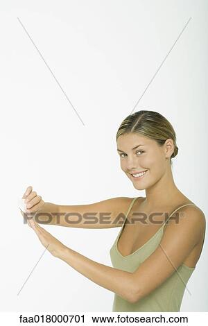 Stock Image - Young woman removing finger polish from nails. Fotosearch