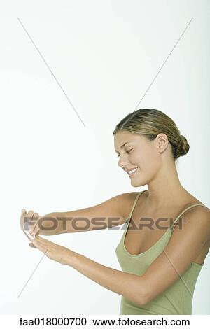 Stock Image - Young woman removing polish from fingernails. Fotosearch