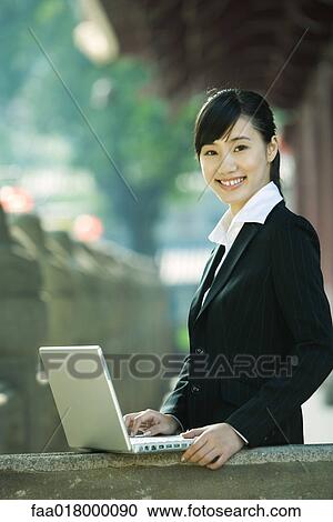 Young woman standing next to laptop, portrait View Large Photo Image Stock Image - Young woman standing next to laptop, portrait. Fotosearch
