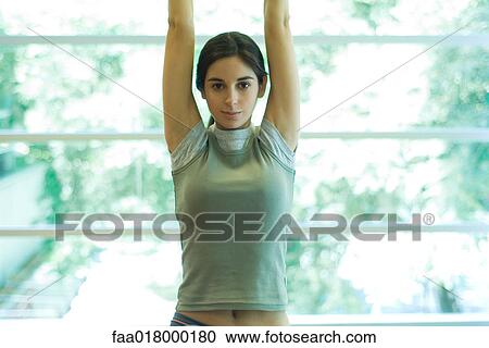 Stock Image - Young woman stretching arms overhead. Fotosearch