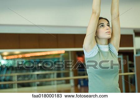 Young woman stretching arms overhead View Large Photo Image Stock Image - Young woman stretching arms overhead. Fotosearch